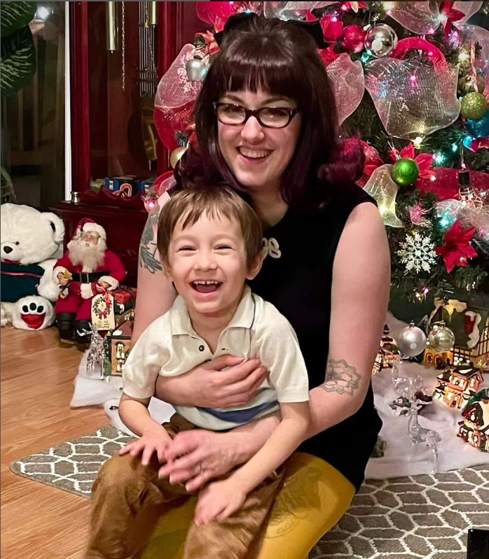 la créatrice charlie et son petit garçon de 4 ans assis sur elle posant devant le sapin de noël. 